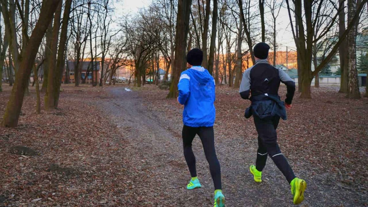 People Running in a Leaf-Covered Park Trail