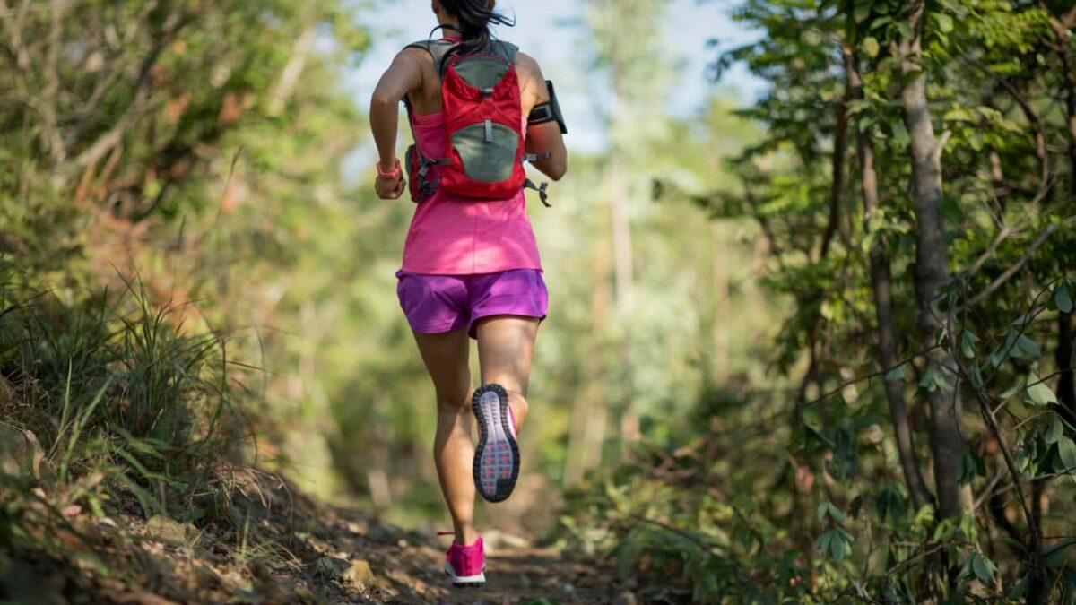 How I Stopped Treating the Trail Like a Treadmill and Finally Started Running It Woman trail runner running in forest trail with vest
